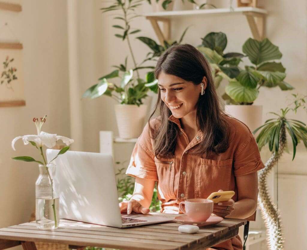 Female remote worker happily working at home; remote employee perks concept