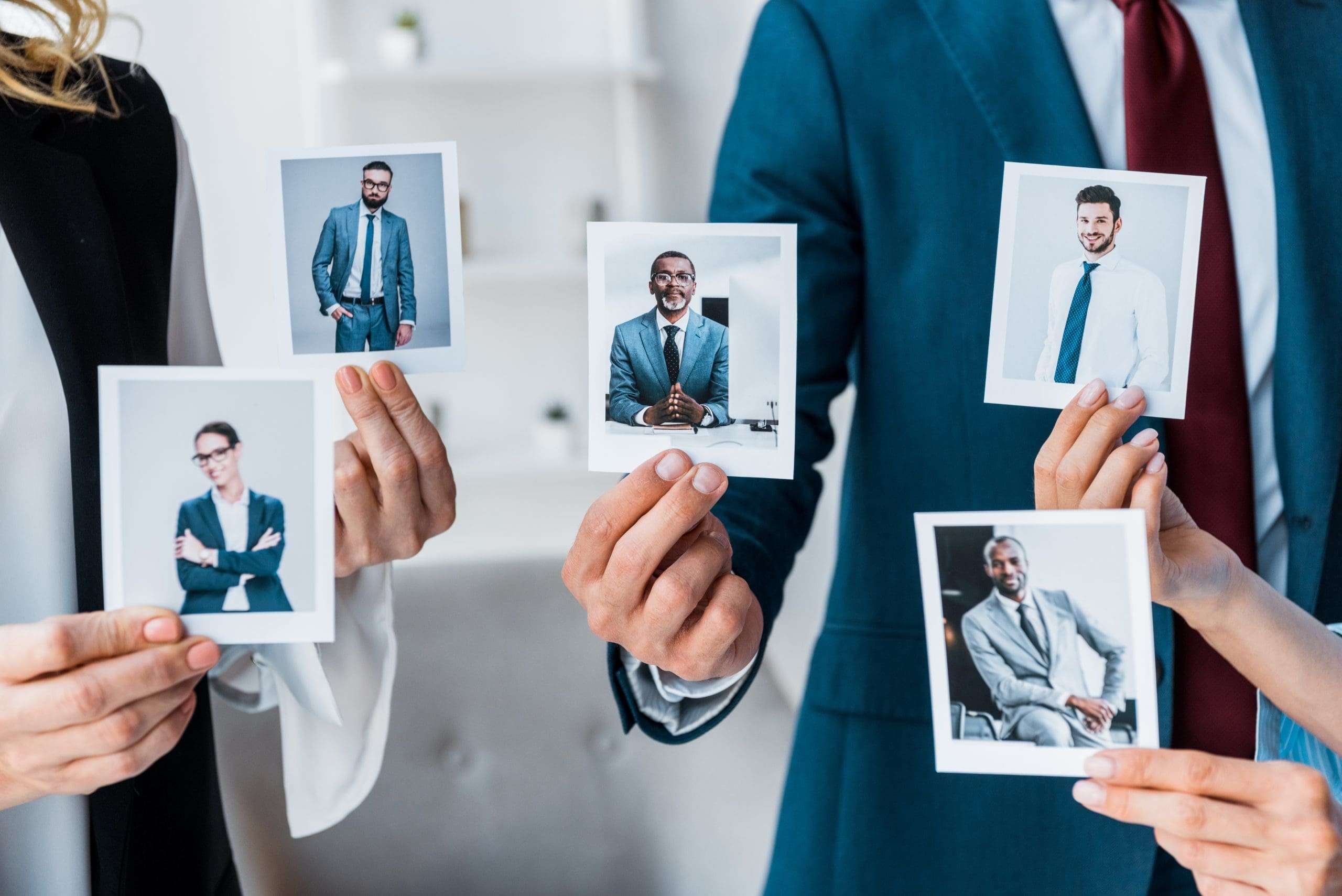 well dressed business people holding photographs