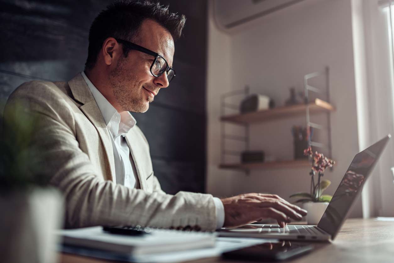 Businessman participating in virtual teamwork while using his laptop at home.