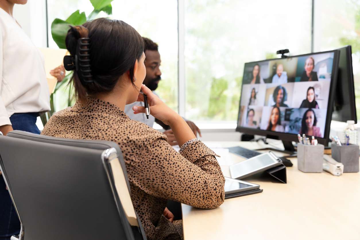Team building for remote workers - Employees in an office having a project meeting with their colleagues working remotely.