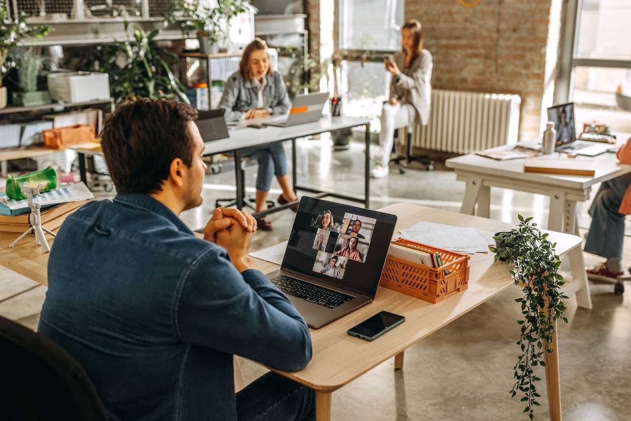 Working with internal remote teams - A male employee speaking with his colleagues through his laptop.