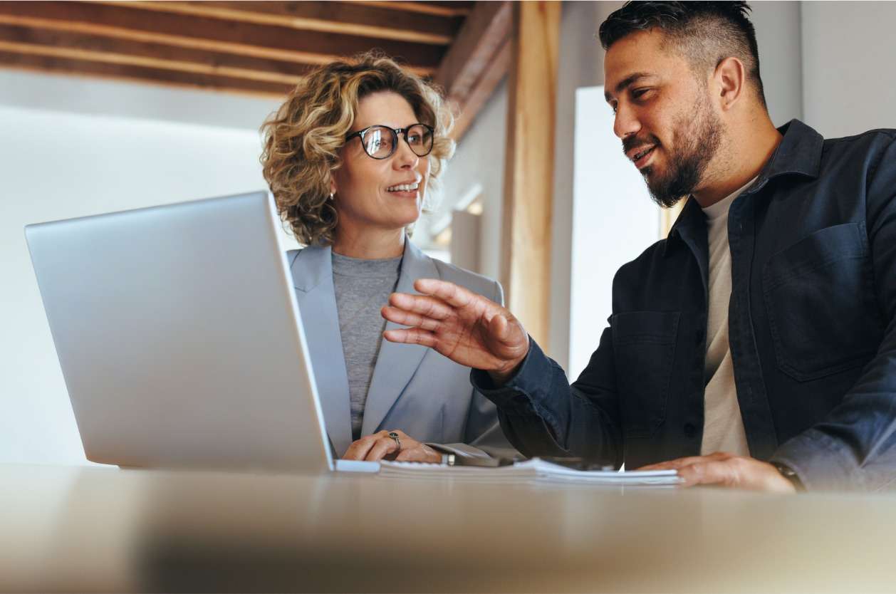 EOR services for your business requirements - Two business owners using a laptop while discussing business strategies.