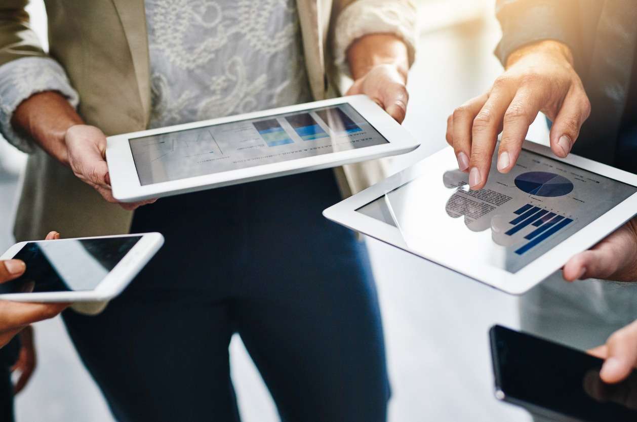 Global workforce management technology - A group of employees using different gadgets while working on a project.