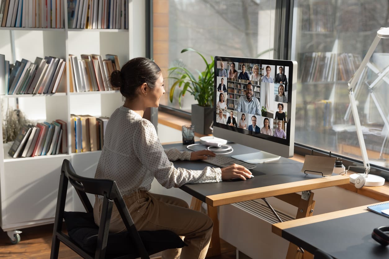 Remote onboarding tools and technology - A female employee working at home while having a virtual meeting with her colleagues.