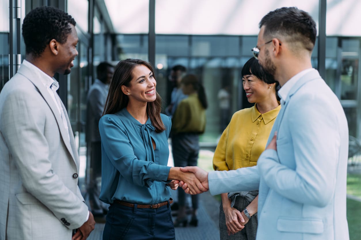 Cross-border recruitment - A businesswoman shaking hands with a newly hired male employee.