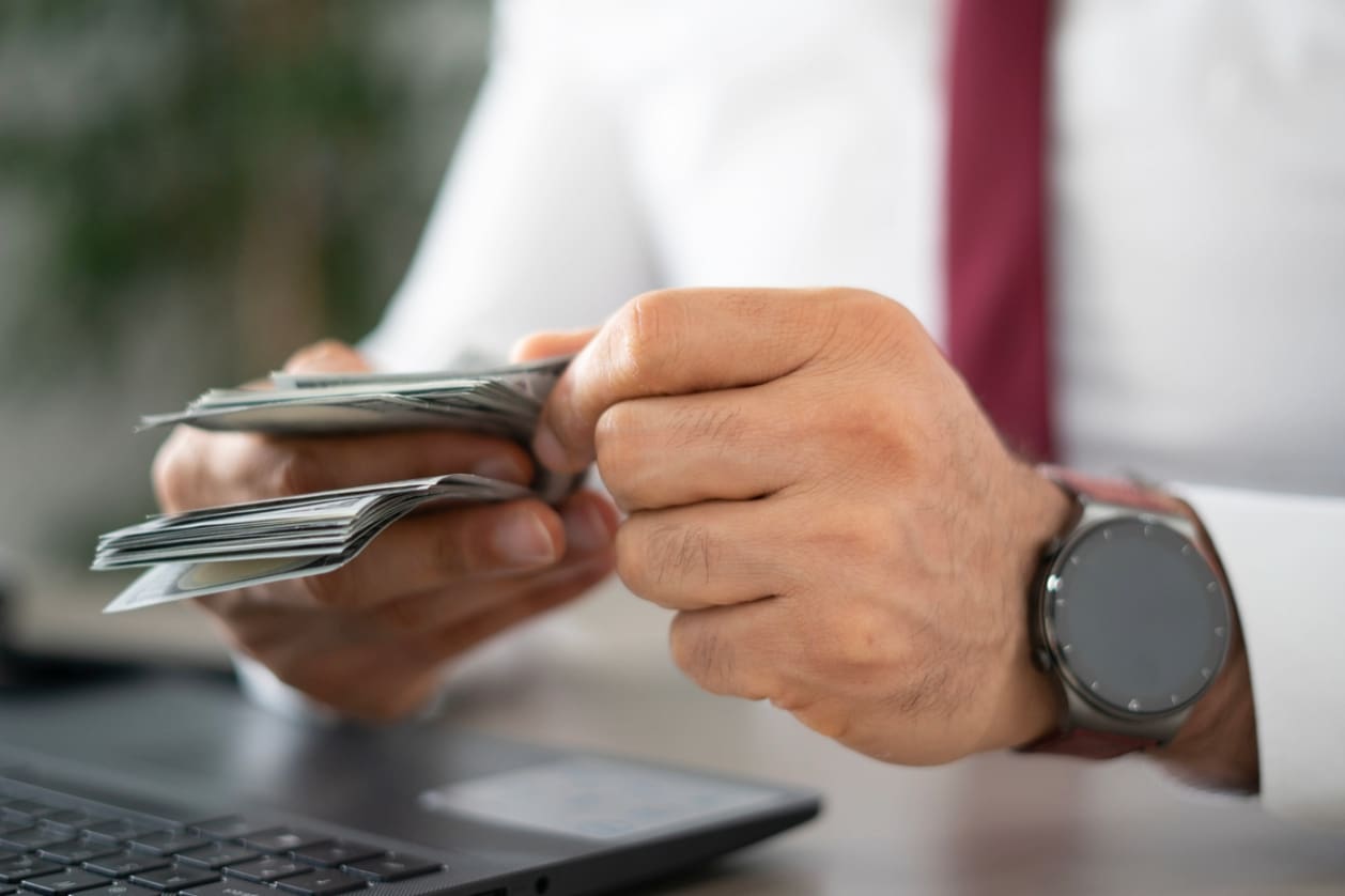 Hiring in Canada- A U.S.-based businessman counting US dollar bills.